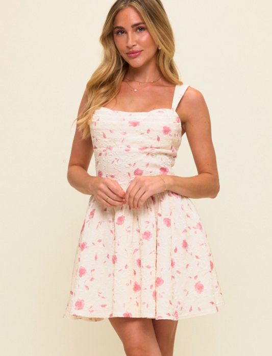Woman wearing a floral pleated bust fit and flare mini dress on a beige background