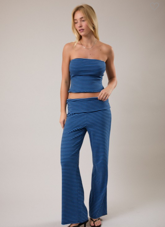 Woman wearing a blue striped tube top and pants on a gray background